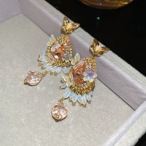 Macro detail of vintage butterfly earrings with champagne crystals and beaded tassels