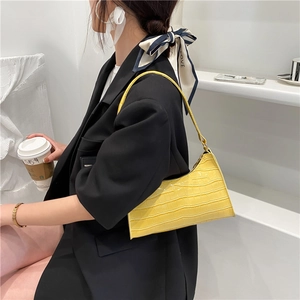 Minimalist yellow crocodile pattern baguette bag worn by model in chic black blazer outfit
