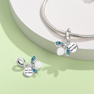 Macro view of firefly charm with green wings and 'You are my light' engraved silver tag