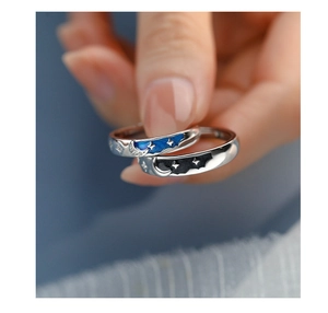 Close-up of star and moon couple rings with blue and black enamel starry sky detail