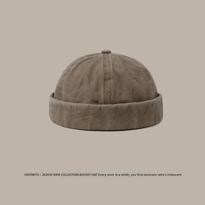 Detail view of washed cotton fabric and dome button on this brown docker brimless hat