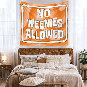 Detail of bohemian orange tapestry with No Weenies Allowed text in a cozy bedroom