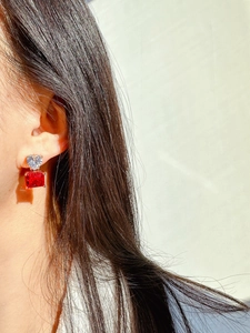 Macro detail of heart-shaped zircon and rectangular red stone earring on ear