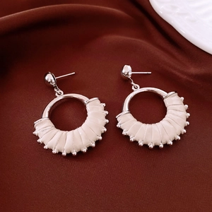 Close-up of vintage round earrings with cream leather wrap and silver metal bead accents