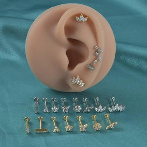 Détail de clous d'oreilles en acier inoxydable argenté et doré avec motifs papillon et feuille
