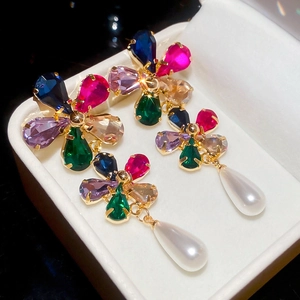 Macro shot of colorful zircon flower earrings with a white teardrop pearl drop pendant