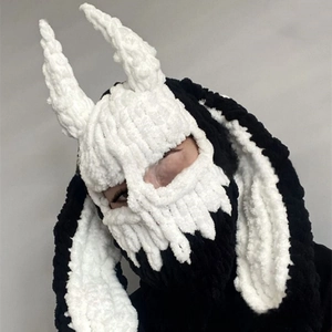 Macro shot of hand-knitted balaclava with white devil horns and long floppy ears