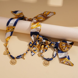 Close-up of golden necklace featuring silk scarf weave and sun heart elephant charms