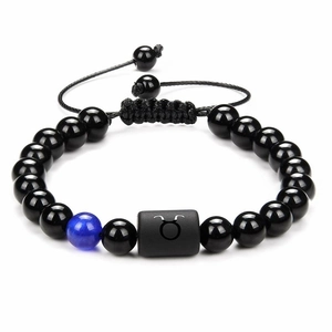 Detailed close-up of Taurus zodiac charm on black onyx beaded bracelet with adjustable cord