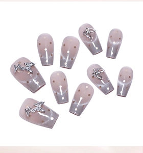 Macro detail of French cat eye press-on nails with 3D silver butterflies and polka dots