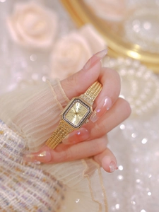 Elegant gold-tone square watch with diamond bezel and woven strap on female wrist