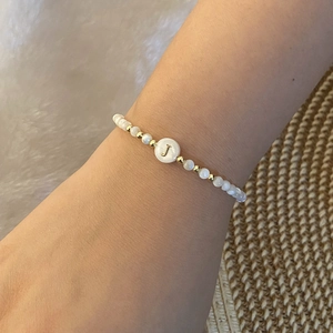 Detail of beaded bracelet with white pearls and a gold letter J charm on wrist