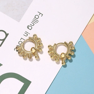 Detailed view of classic golden ball hoop earrings on a stylish tricolor background