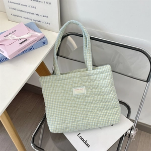 Détail de la couture en cœur sur un sac cabas matelassé à carreaux bleu et jaune