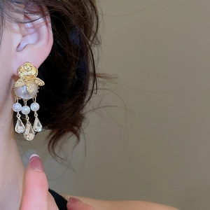 Detail of vintage flower stud earring with large white pearl and crystal drop on model