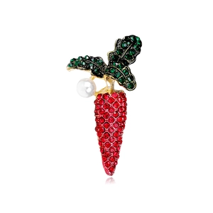 Detailed view of carrot brooch with red and green rhinestones and a white pearl accent