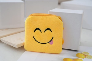 Close-up of yellow plush coin purse with detailed smiling face embroidery texture