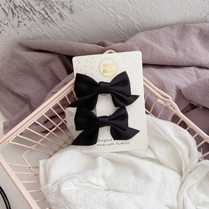 Gros plan de barrettes nœuds en tissu noir fait main présentées sur une carte blanche