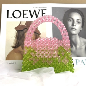 Close-up of pink and green beaded handbag on a magazine for a stylish summer look