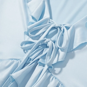 Detailed view of light blue ruffle dress with tie-up bow and soft fabric texture