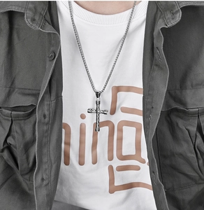 Close-up of a twisted silver stainless steel cross pendant necklace on a male model