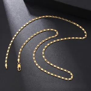 Detail of a gold-plated flat link necklace with a lobster clasp on a dark background