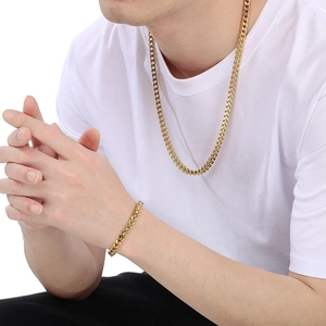 Close-up of a model wearing a golden stainless steel Cuban link necklace and bracelet set