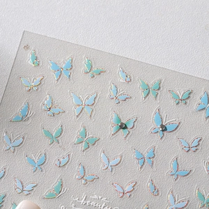 Adhesive butterfly nail stickers featuring light blue and teal iridescent glitter designs