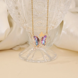 Elegant gold butterfly necklace with purple gradient wings and zircon on a crystal glass
