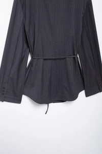 Detail view of dark gray textured blazer back with thin waist belt and cuff buttons