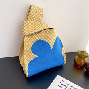 Detail of yellow and white checkerboard knit bag with blue floral patterns and soft texture
