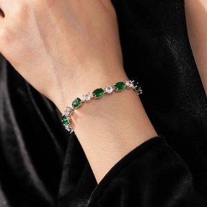 Détail d'un bracelet argenté avec pierres précieuses vertes et claires porté au poignet