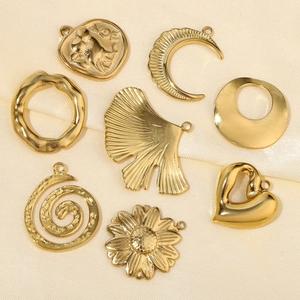Golden titanium steel charms in heart, leaf and moon shapes on beige silk fabric