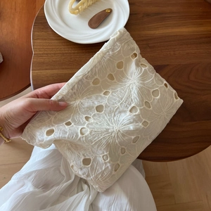 Close-up of beige lace embroidery and hollowed-out floral pattern on a fabric bag