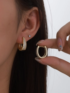 Detailed close-up of gold-plated oval hoop earrings featuring micro-pave white zircon stones
