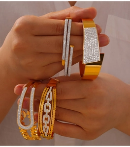 Vue détaillée de quatre bracelets en acier titane doré aux motifs géométriques et zircons