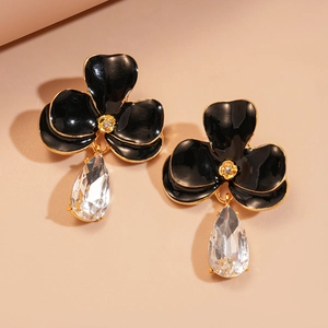 Détail de boucles d'oreilles fleuries avec émail noir, cristaux et pendentifs gouttes
