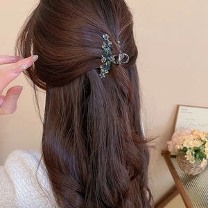 Détail d'une pince à cheveux vintage fleurie en strass portée sur de longs cheveux bruns