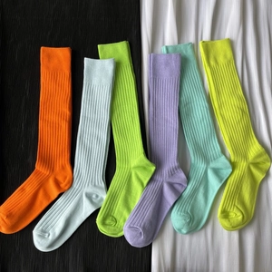 Flat lay of six colorful ribbed knit crew socks on a pleated monochrome background