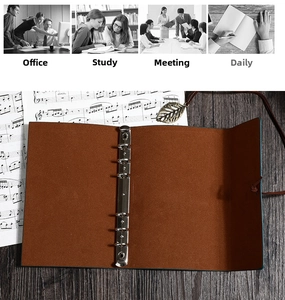 Detail of vintage leaf pendant and silver 6-ring binder on brown leather journal