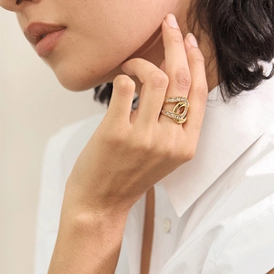 Détail d'une bague ajourée plaquée or 18 carats avec strass portée sur le doigt d'un mannequin