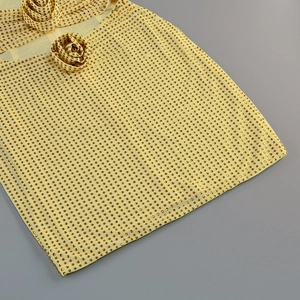 Détail de la robe jaune avec des clous dorés et des fleurs décoratives au col
