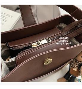 Detail of smooth metal zipper and magnetic buckle on dark brown leather bucket bag