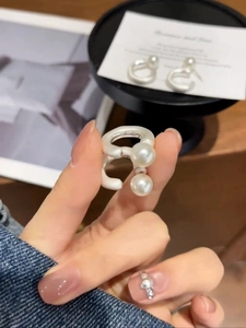 Close-up of double pearl silver hoop earrings held by hand in an elegant lifestyle setting