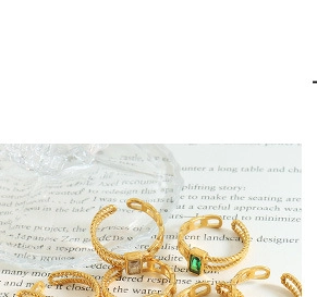 Detailed shot of gold-plated open rings with green and white emerald-cut gemstones