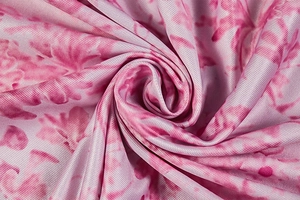Gros plan sur tissu floral rose montrant une texture douce et des détails tissés