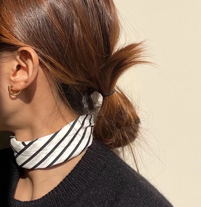 Minimalist oval gold earring and striped neck scarf styled on a black sweater