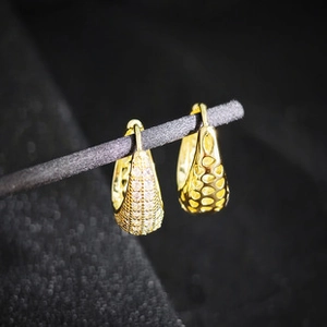Vista de detalle de pendientes cuadrados dorados con circonitas y diseño de malla hueca