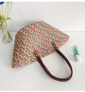 Detail of colorful woven straw tote bag with premium brown leather handles for summer beach