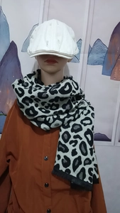Fashionable leopard print scarf in black white and grey worn by model with newsboy hat